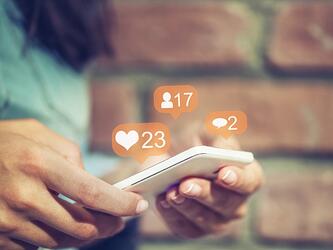 person using phone with social icons